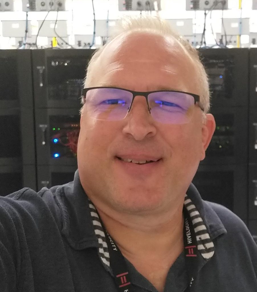 Todd Pree standing in front of racks of servers at a data center in Tampa, FL, overseeing high-performance computing and data infrastructure.